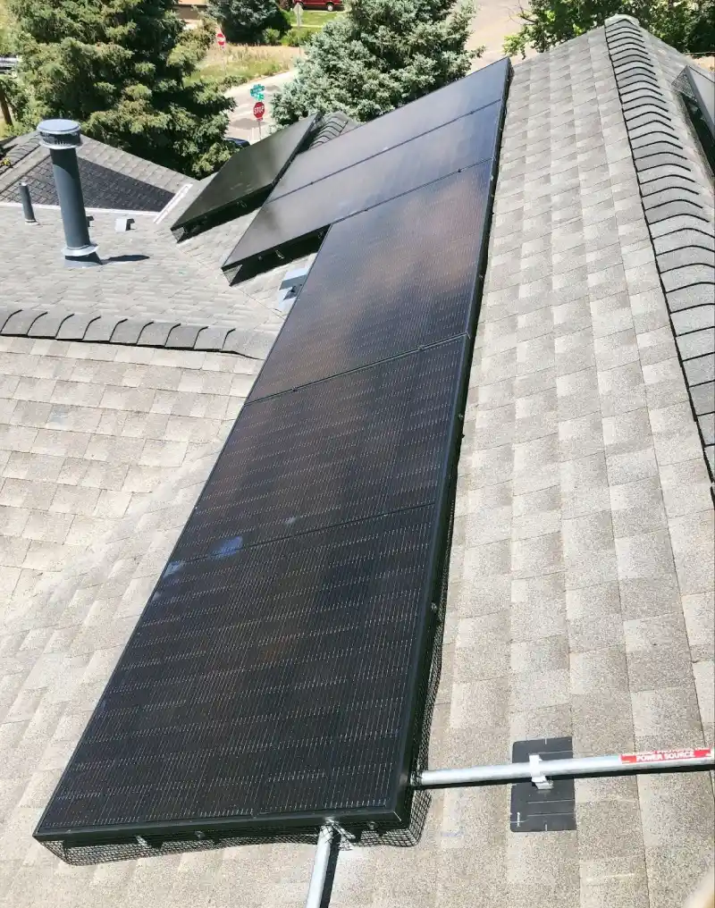 Close-up view of black solar panels on an asphalt shingle roof, showcasing clean energy solutions for Erie homeowners