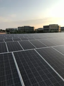Flat roof solar panel system with distant commercial buildings in view under clear Colorado skies