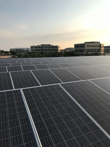 Flat roof solar panel system with distant commercial buildings in view under clear Colorado skies