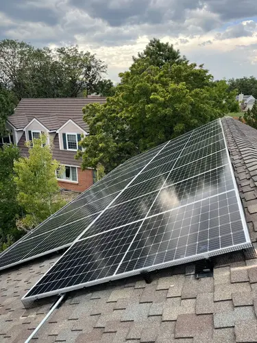 Solar panels on a Boulder rooftop with greenery and cloudy skies, highlighting clean energy use